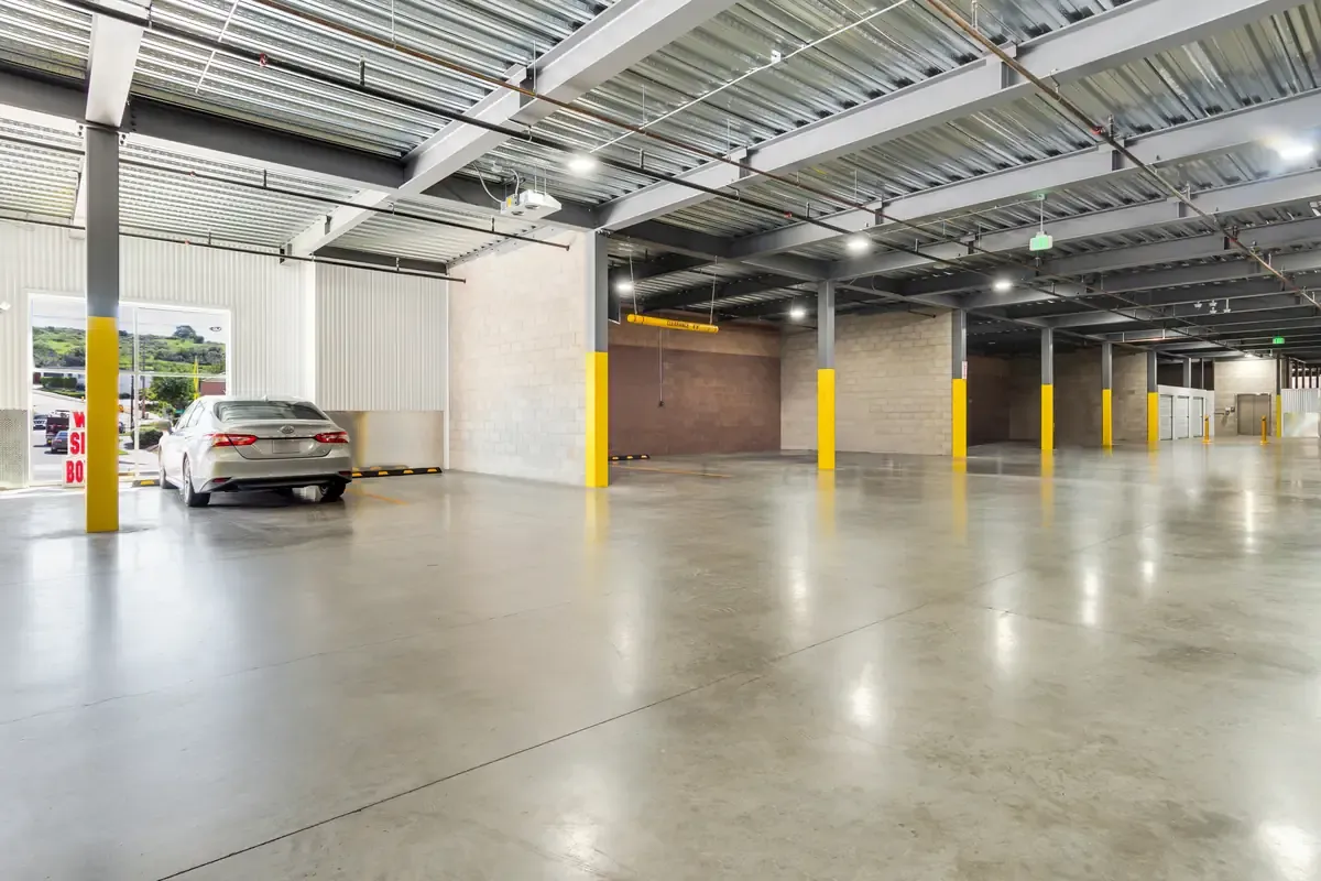 Indoor drive-thru unloading bay featuring overhead clearance bars and yellow support posts.