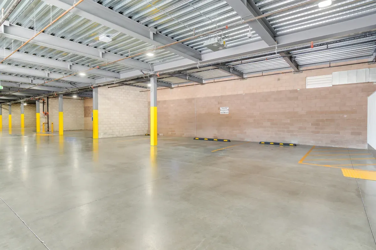 Indoor covered drive-thru unloading bay featuring support pillars, concrete floor, and parking blocks.