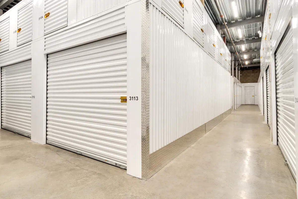 Indoor climate-controlled self-storage unit with white roll-up door and diamond plate corner trim.